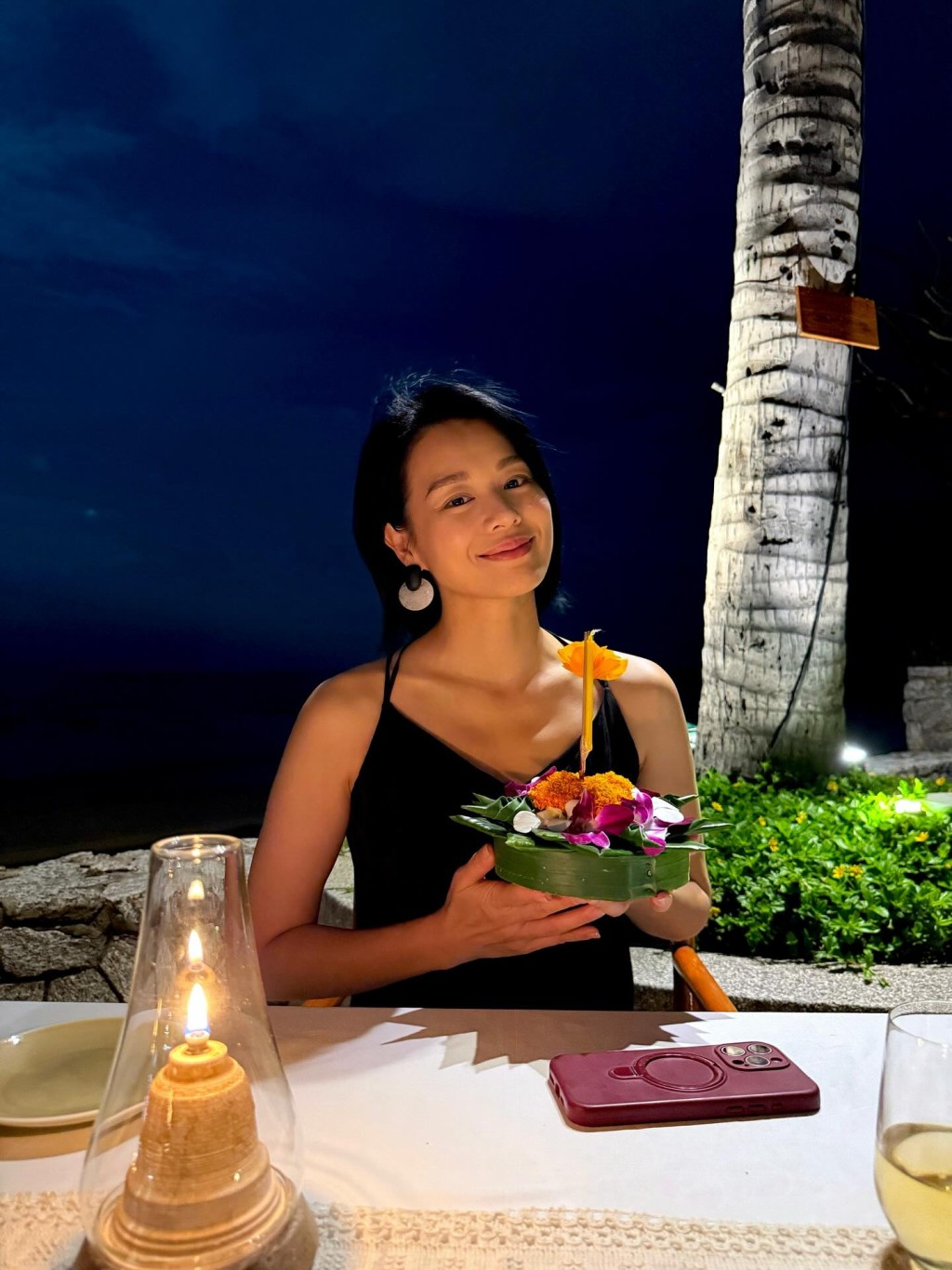 胡杏兒手持泰國傳統花藝供品，面露笑容。