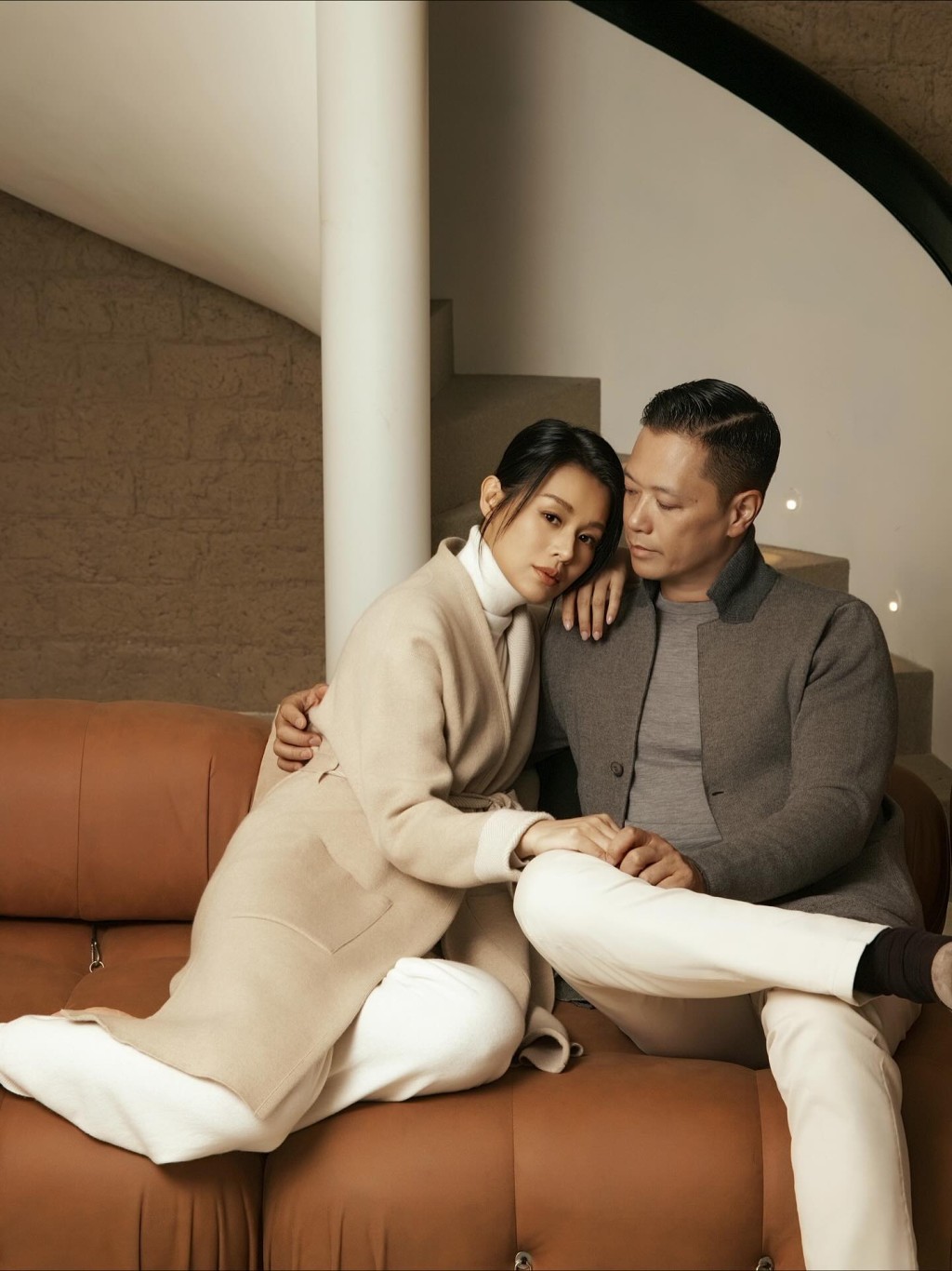 兩夫妻坐在沙發上，李乘德低頭望着胡杏兒，雙手輕牽，十分恩愛。