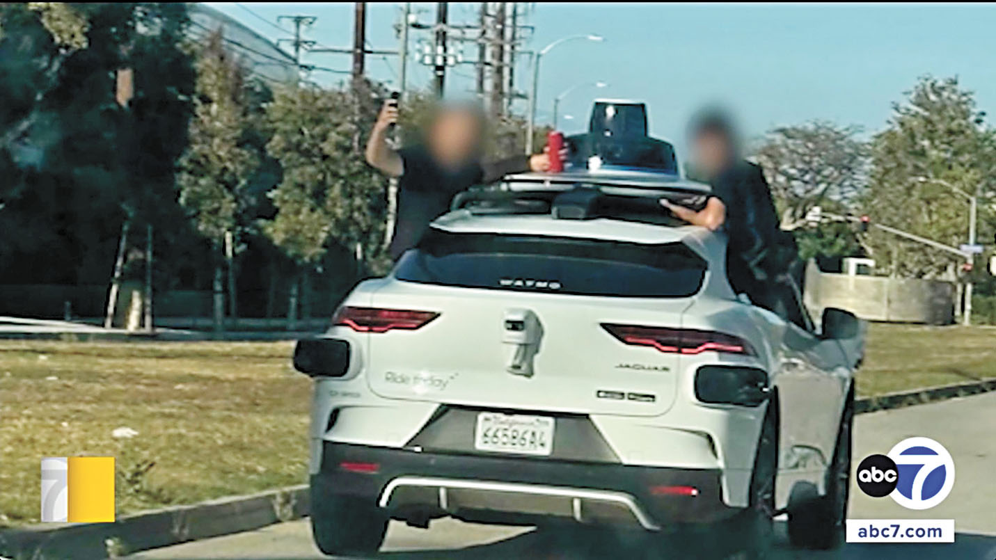 幾個青少年掛在Waymo自動駕駛車的車身外側嬉鬧。ABC7電視畫面
