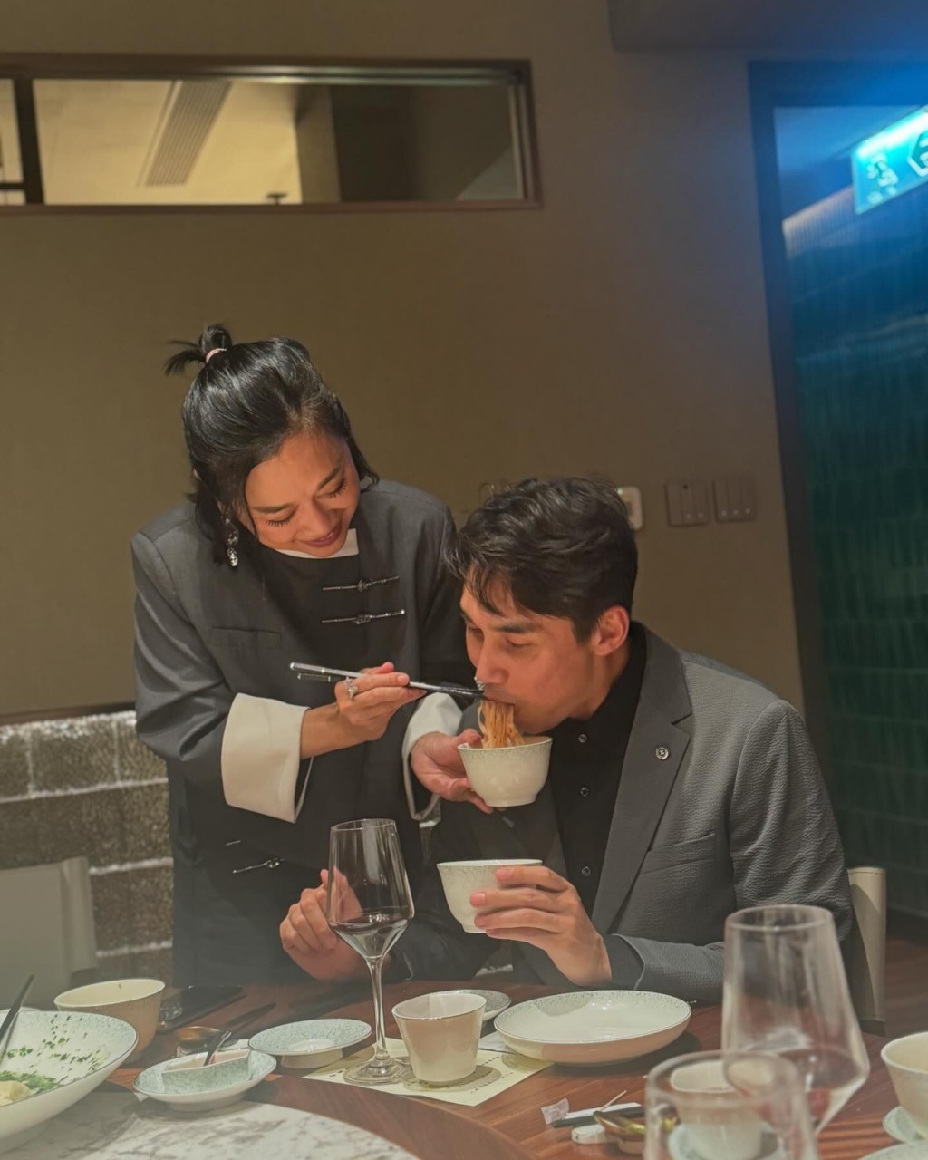 陳松伶站在張鐸身旁，一手拿碗，一手夾起長壽麵餵丈夫，場面甜蜜。