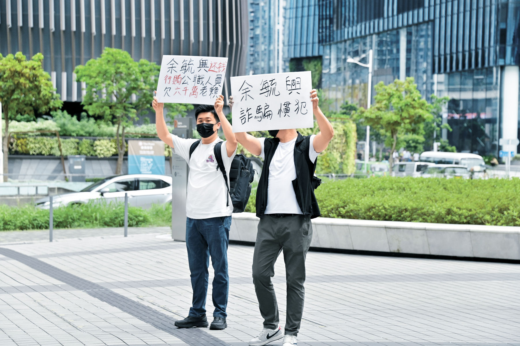 有人在余毓興受訪時舉起手寫橫額示威。