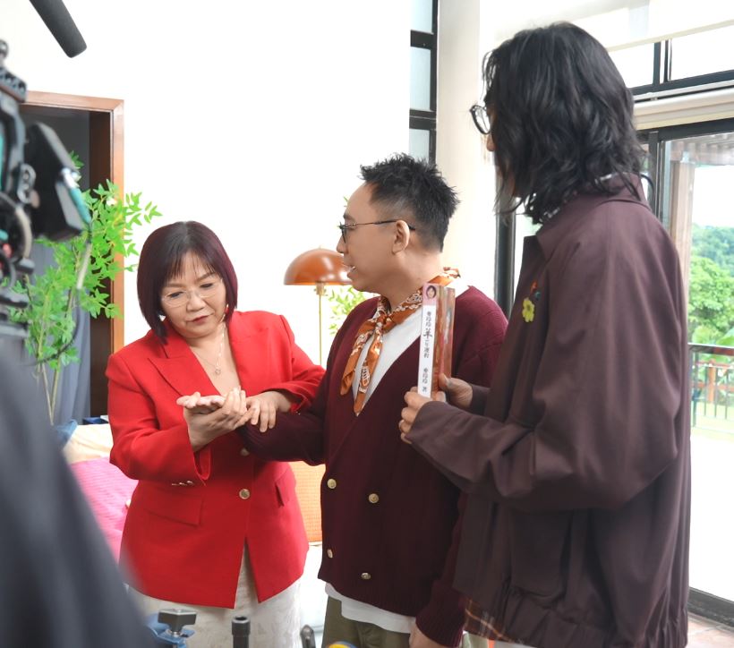 麥玲玲在拍攝空檔為C君觀看掌相。