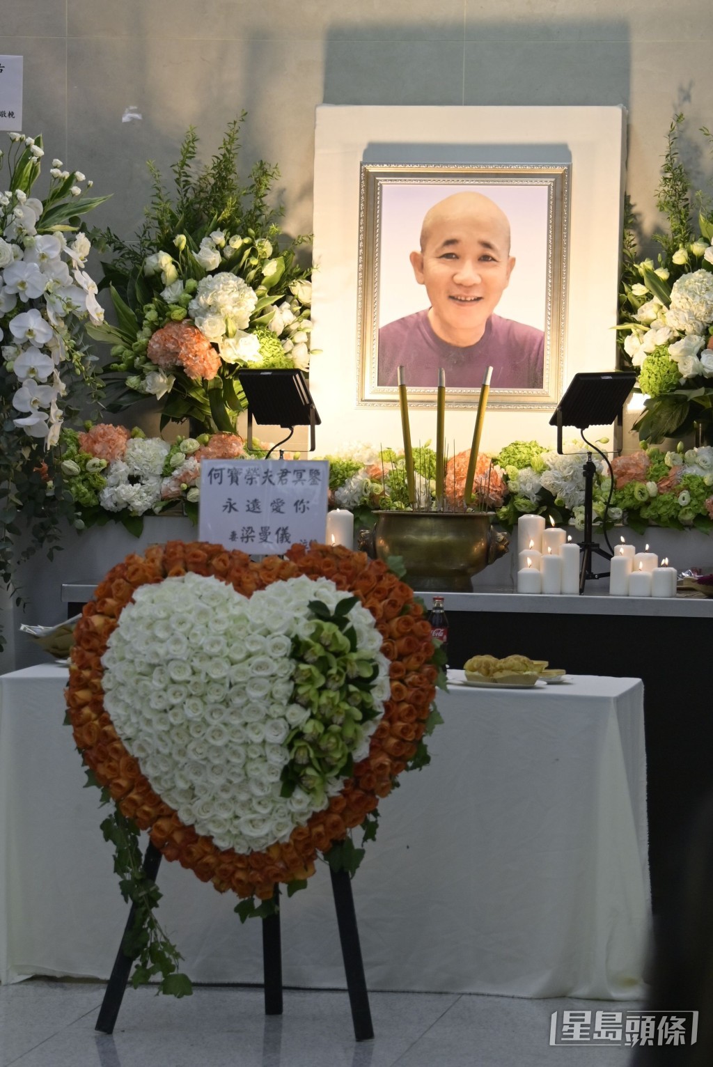 靈堂中央擺放著何寶榮面帶笑容的彩色遺照,佈置簡潔。