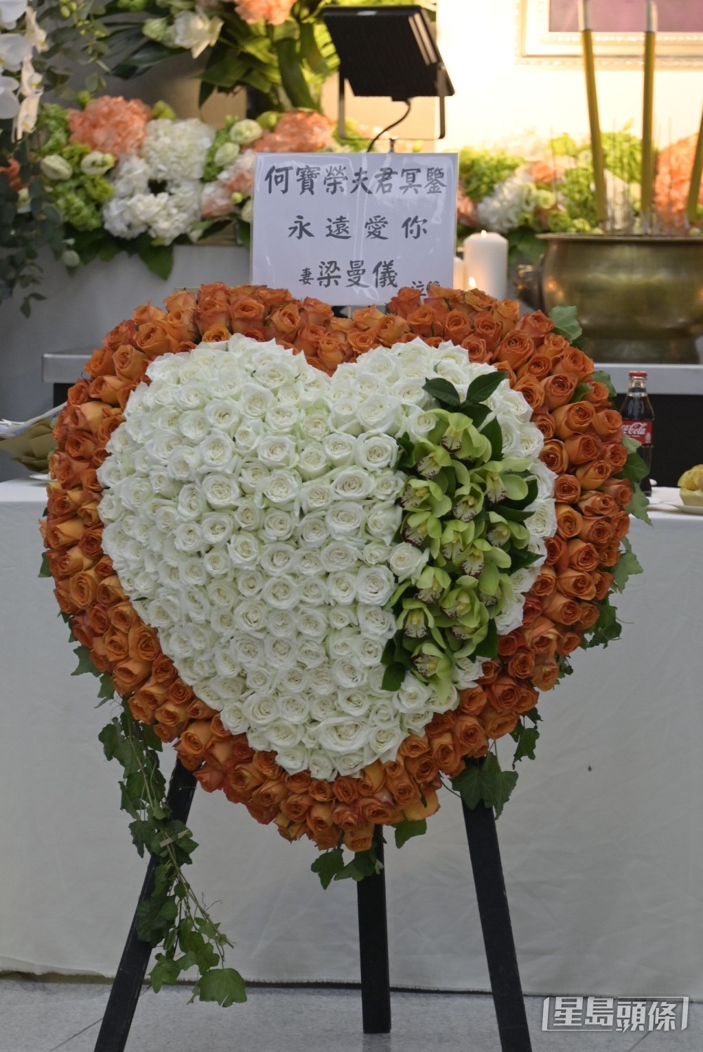 遺孀何梁曼儀致送的心形花牌,擺放在遺照前方,寫上「永遠愛你」。
