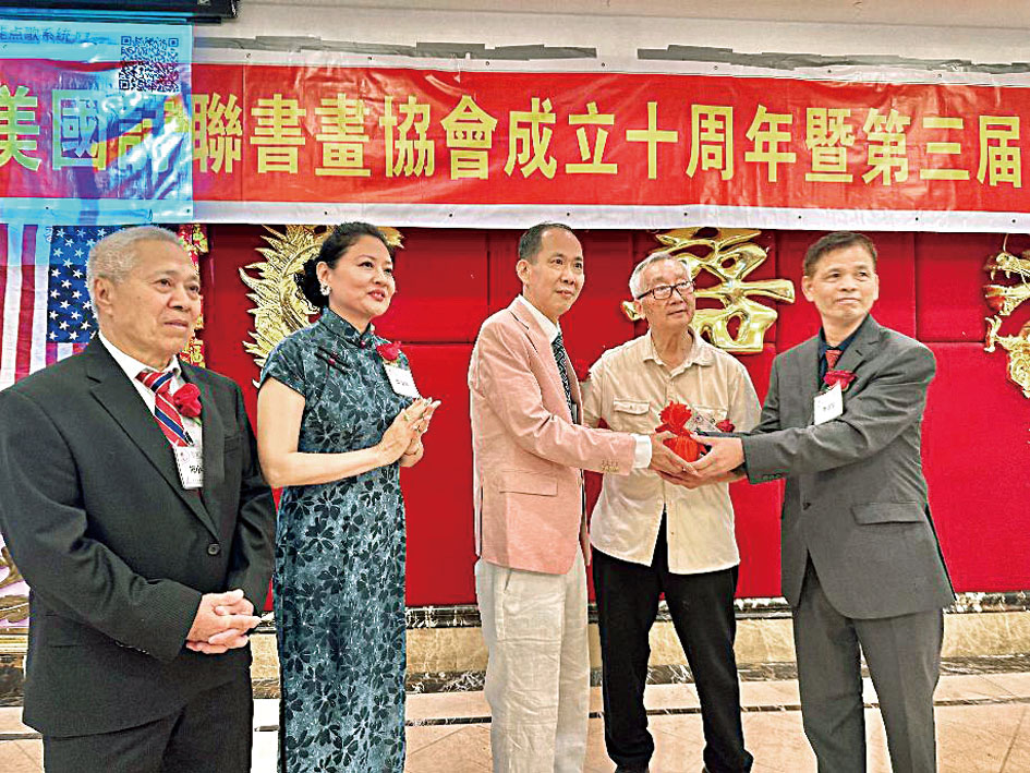 美國詩聯書畫協會新會長梅榕松(中)接過印信。梁敏育攝
