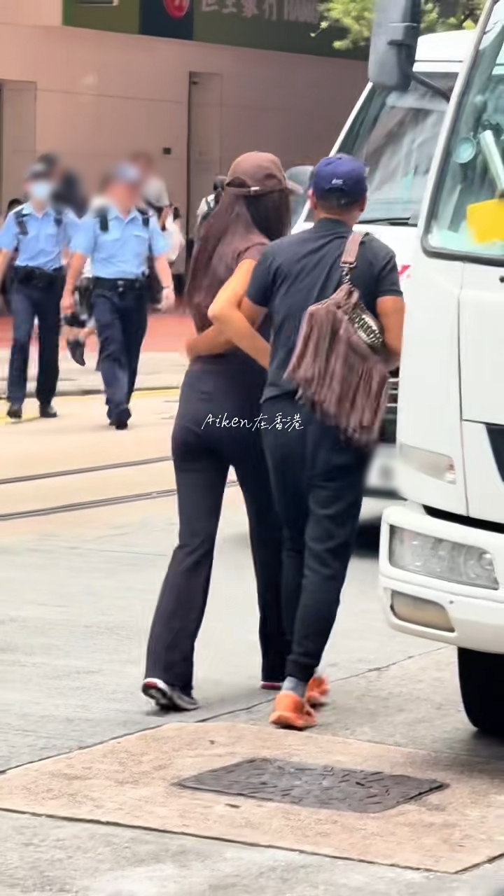 任達華父女在兩架車之間走過馬路。