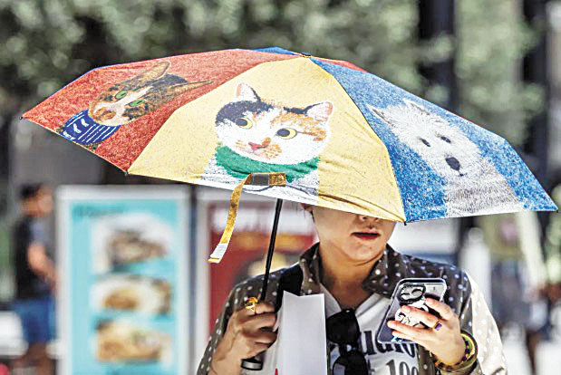 一名行人在洛杉磯市中心烈日下撐傘遮陽。洛杉磯時報