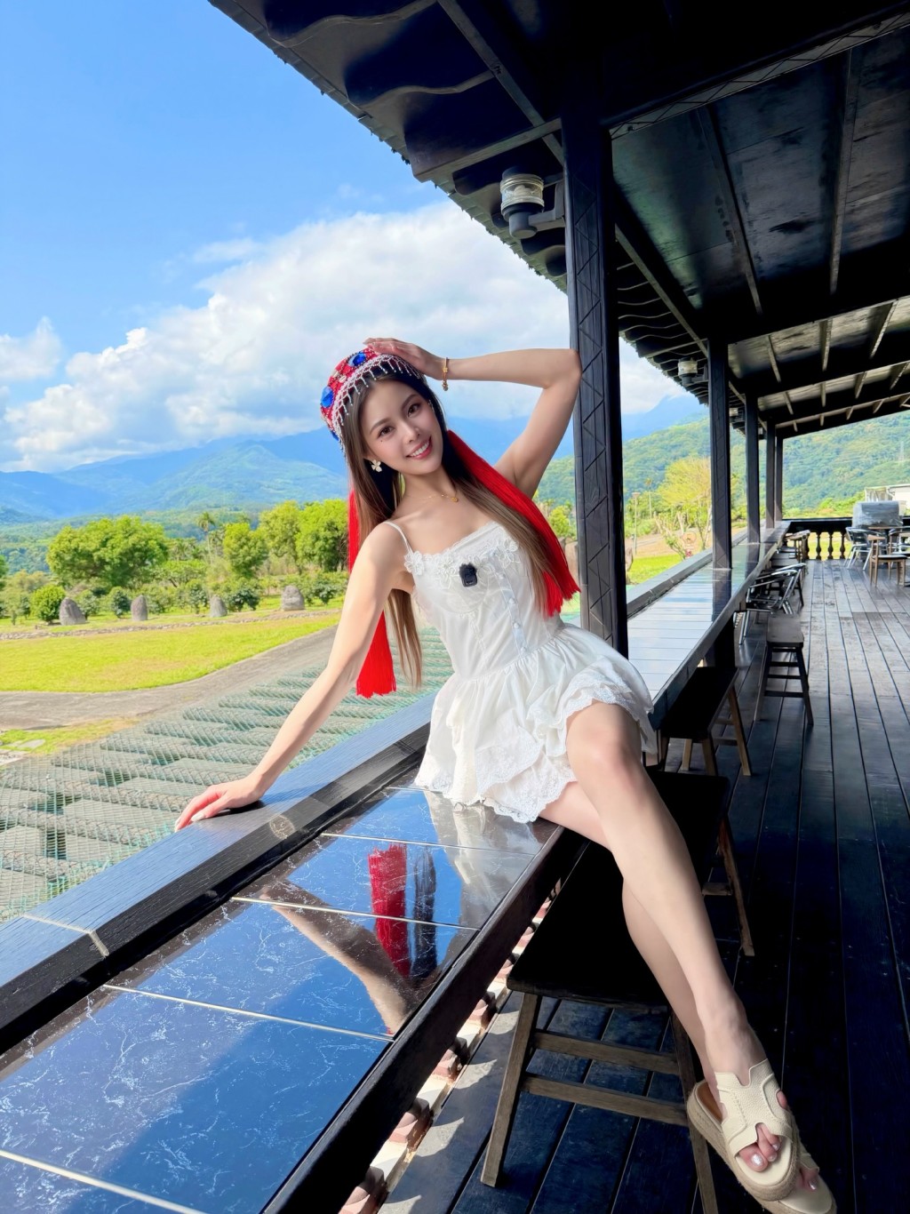 黃瀅仴身穿白色短裙配原住民風頭飾,與山景構成美麗畫面。