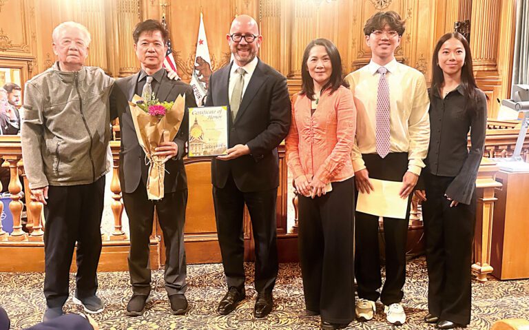 三藩市市參事會主席孟達文（左三）向精英粵劇學院頒發嘉獎狀，創辦人兼音樂總監陳亮斌（左二）與父親、太太及一對子女一同接受表揚。受訪者提供