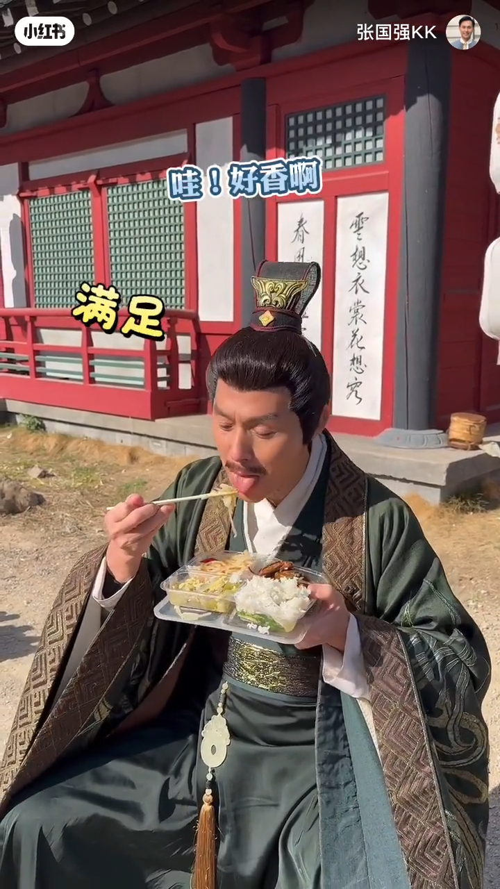 張國強拿著飯盒在路邊用餐。