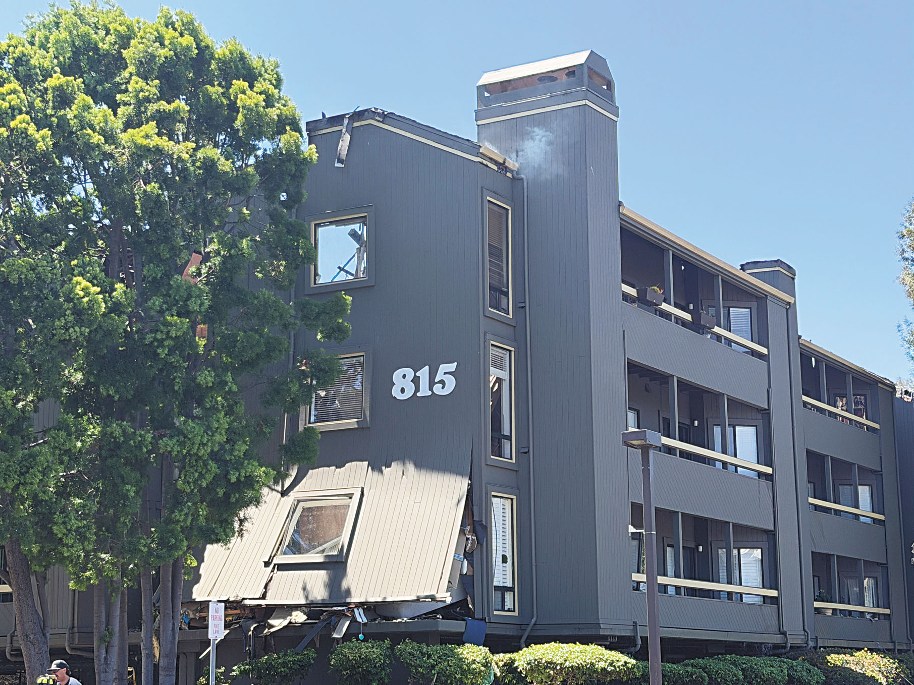 建築物外牆部分坍塌,頂層仍持續冒出白煙。記者蘇婕雅攝