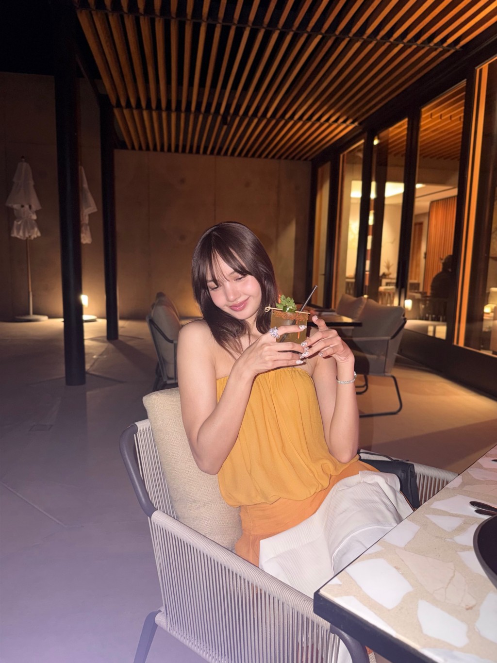 換上黃色晚裝的Lisa,手持飲品享受夜晚的悠閒時光。