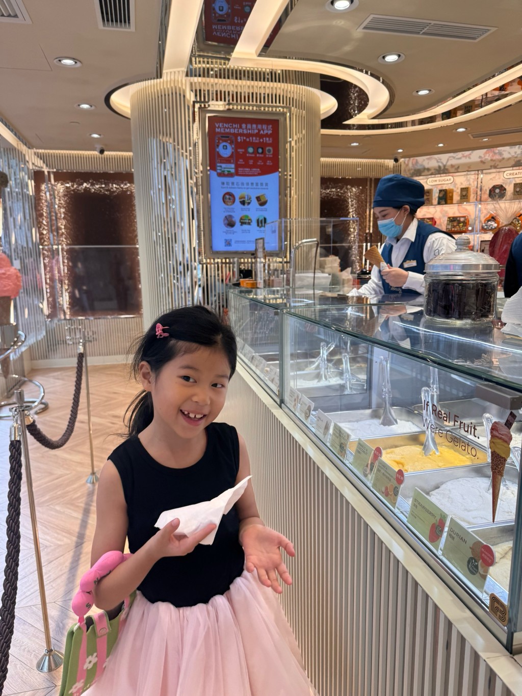 Camellia站在雪糕店前，臉上流露出期待與興奮的神情。