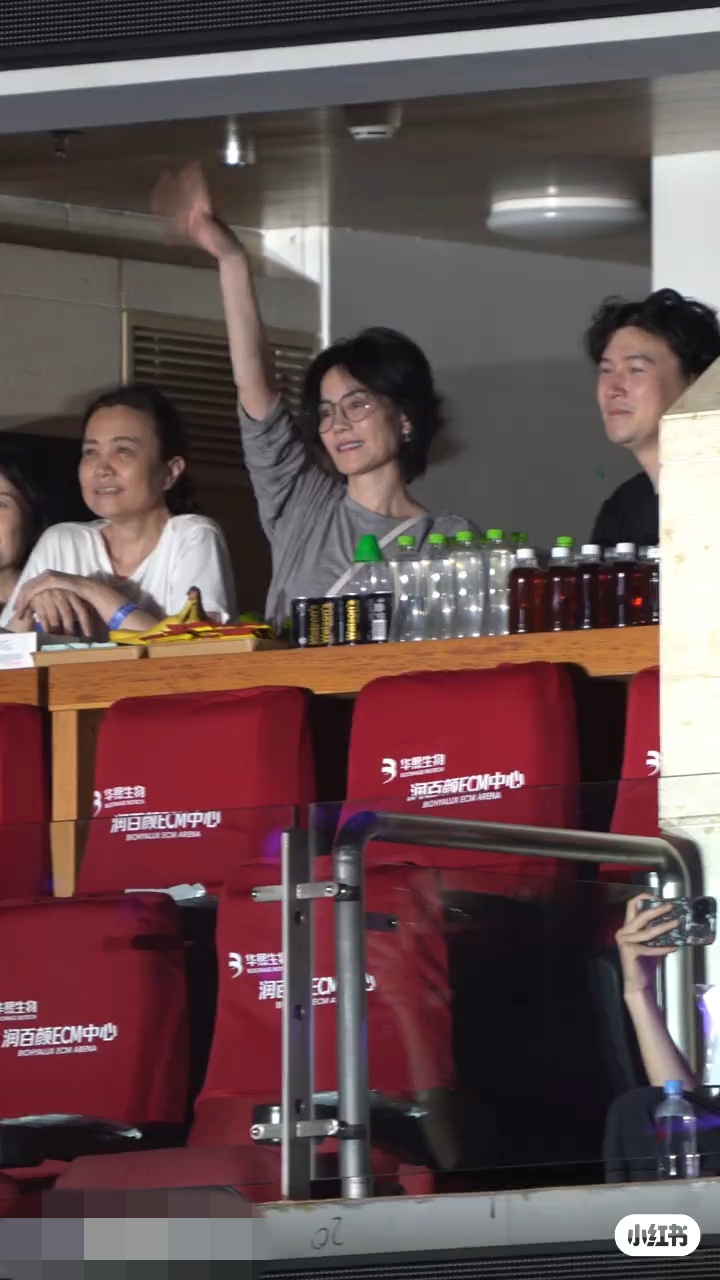 王菲在包廂內向台上的那英揮手打招呼，面露笑容。