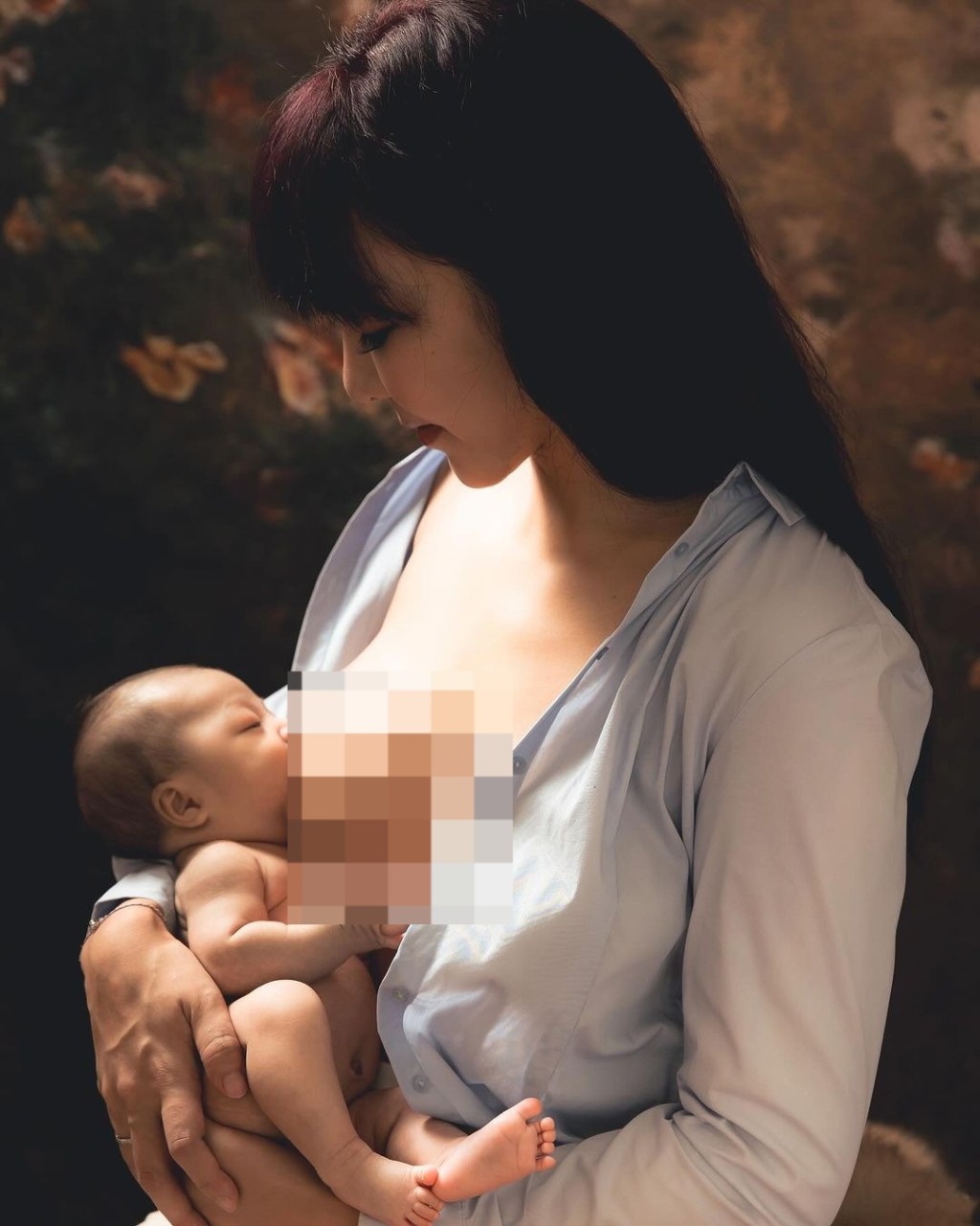 李宓穿上一件淺藍色襯衫，但解開鈕扣露出上圍，並將剛出生的雙胞胎女兒放在大腿上餵母乳，同時遮住重點部位。