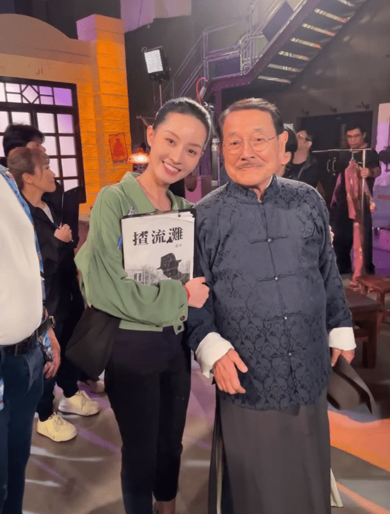 洪曼芹於《愛回家》片場手執《揸流灘》劇本,與劉丹合影。