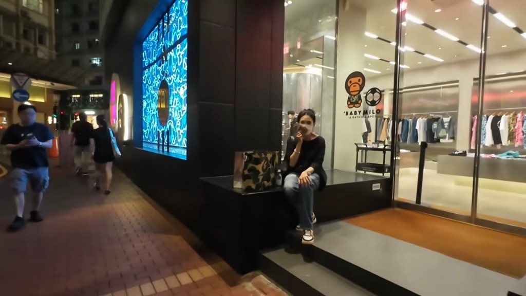 邱淑貞坐在店舖外講電話。(YouTube@SAMSAM週街走)