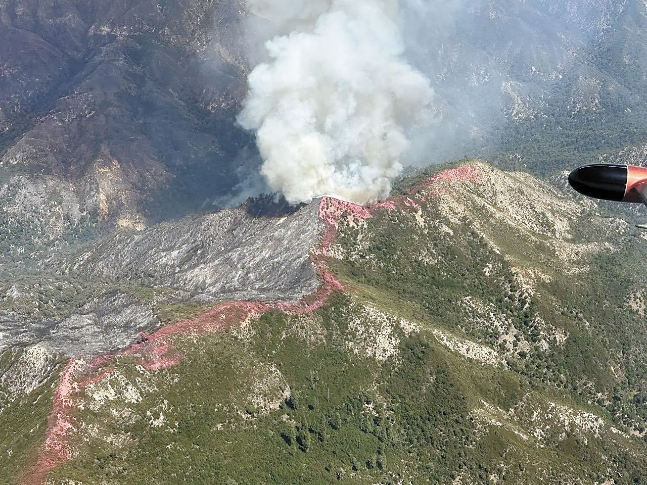 「原木山火」期間，洛斯帕德雷斯國家森林一處偏遠山脊2日仍有火勢燃燒，山頂可見飛機投下的阻燃劑。聯邦林務局圖片