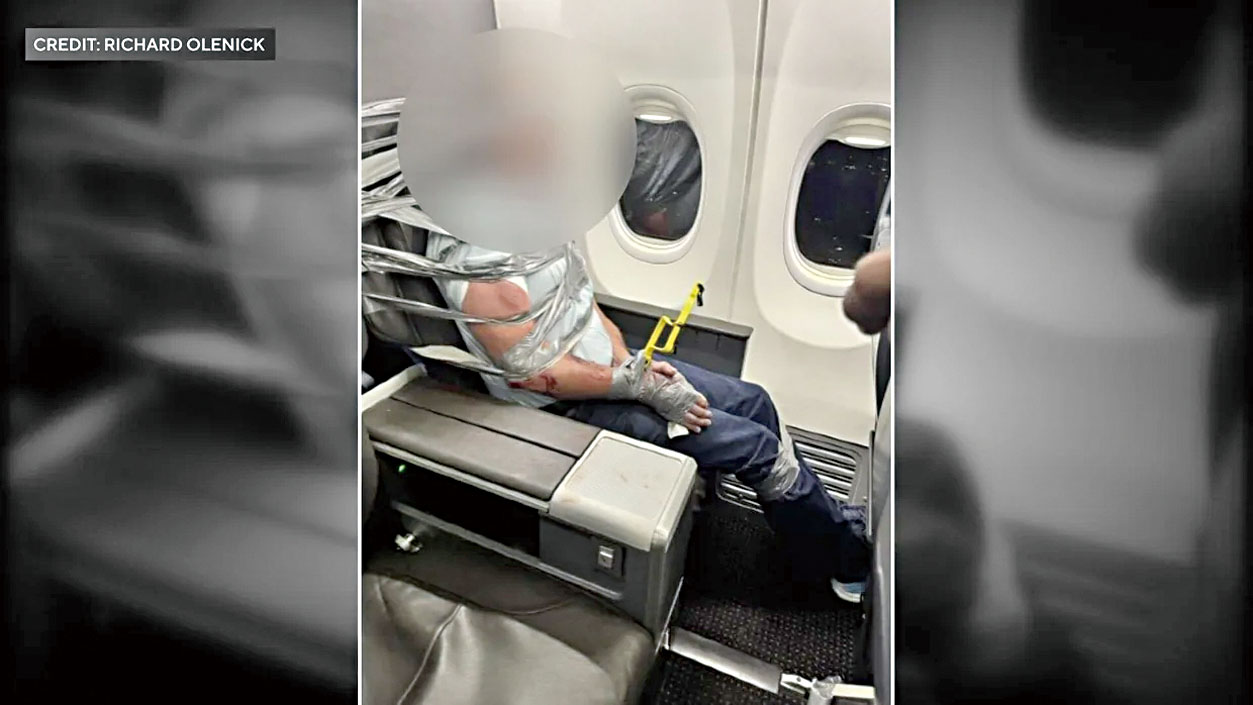 男子遭其他乘客及機組人員以膠帶及束線帶綑綁於座位上。CBS紐約截圖