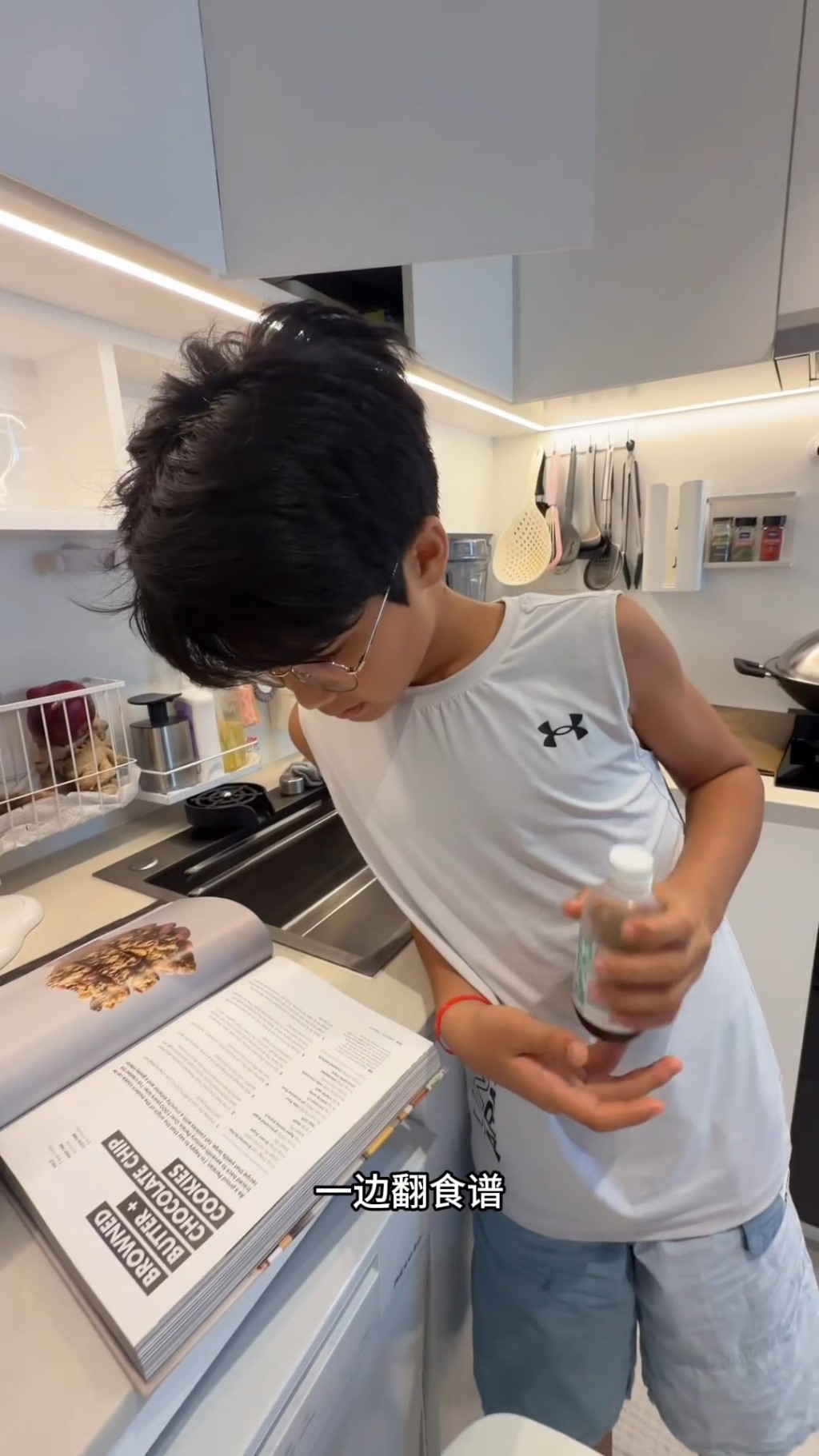 11歲的混血大仔Omi戴上眼鏡，仔細地對照著英文食譜準備材料。