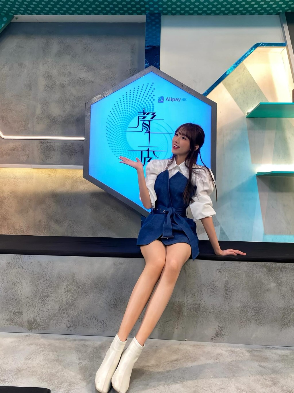 甄敏芳在節目佈景板前留影,展現出修長美腿。