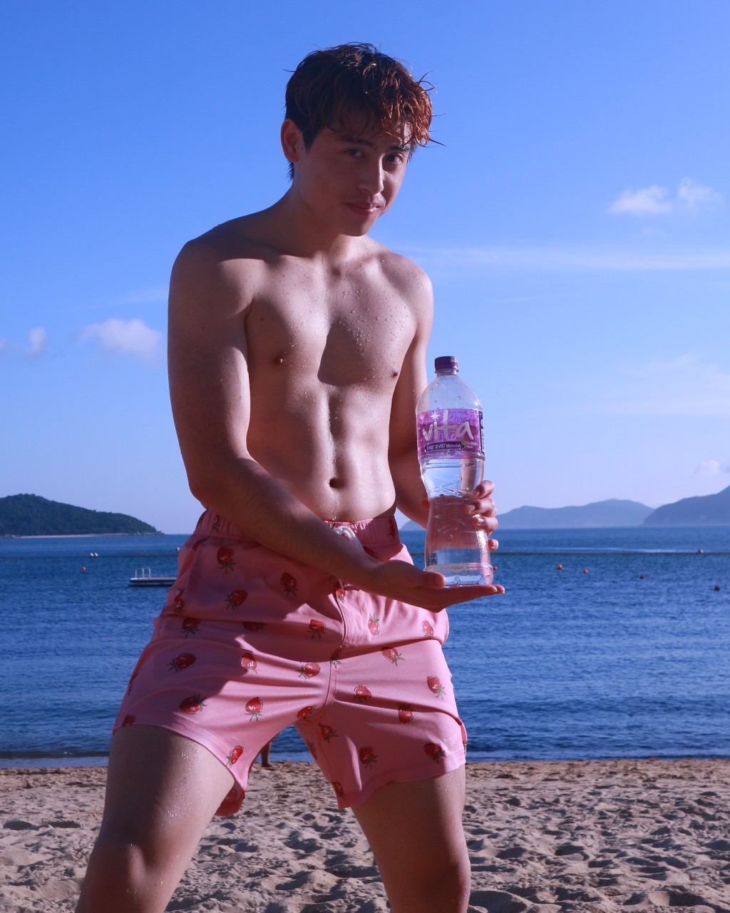 蔡楠手持蒸餾水在沙灘擺姿勢,充滿陽光男孩氣息。