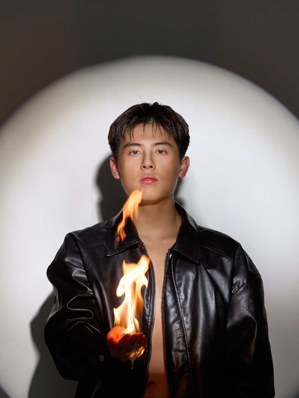 蔡楠身穿黑色皮衣,手捧火焰,畫面充滿視覺張力。