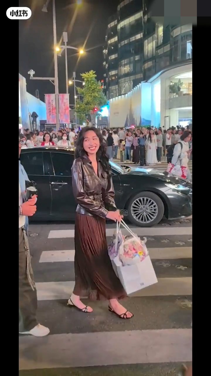 新抱湯暢手持鮮花站在路口,目送奶奶座駕離開,面露禮貌微笑。