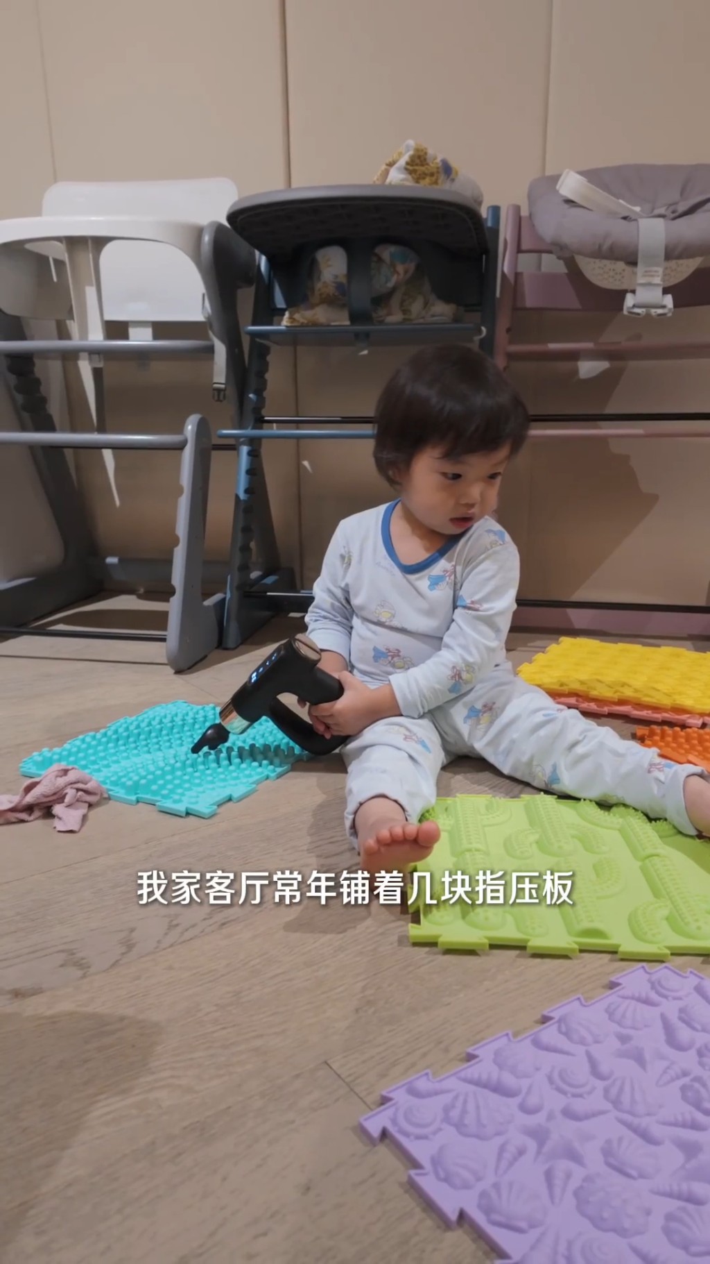 「袁咕碌」坐在指壓板上探索玩具。