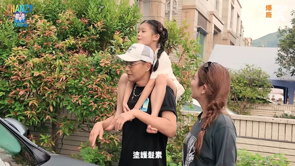 陳展鵬背著女兒，與太太在屋外散步。