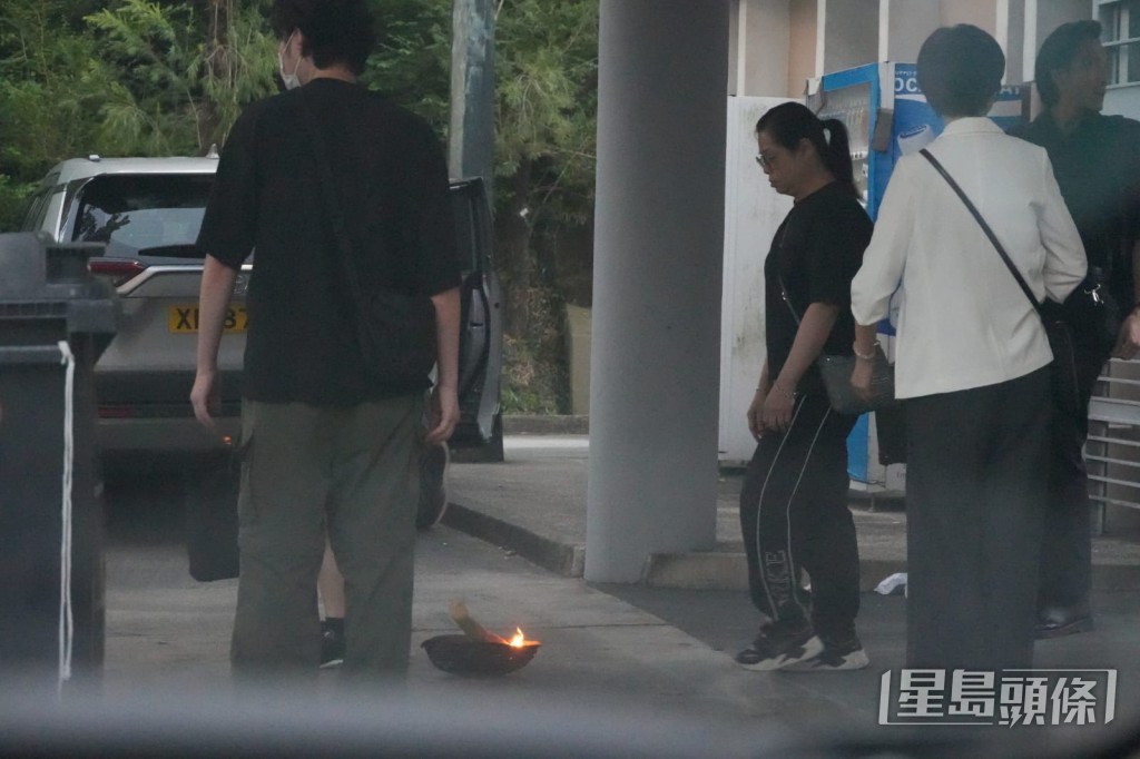 親友按照傳統,在正門外進行「過火盆」儀式,並橫過馬路到化寶爐焚燒祭品。