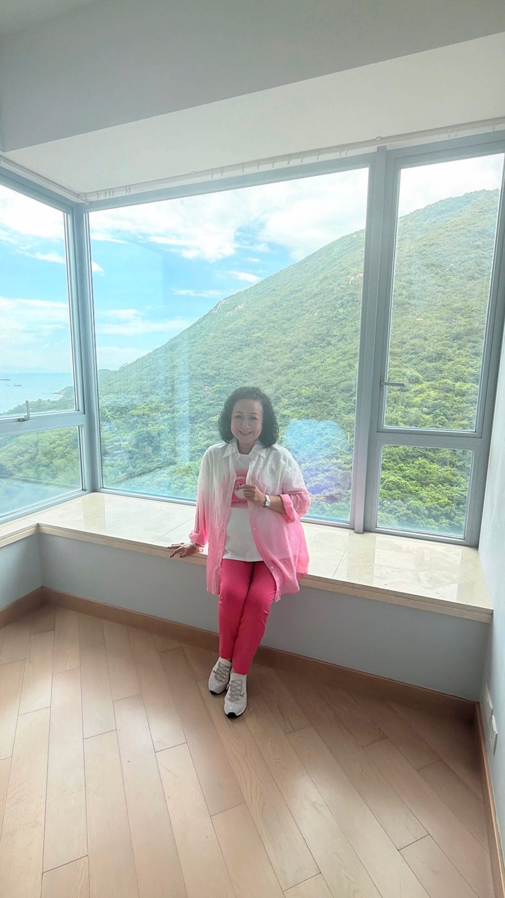 薛家燕安坐於豪宅的落地玻璃窗台上,愜意欣賞窗外山景與海景。