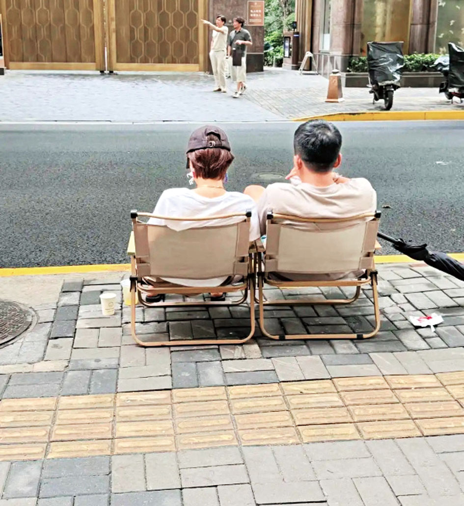 她與一位男士坐在街邊摺疊椅上閒談小聚。網上圖片