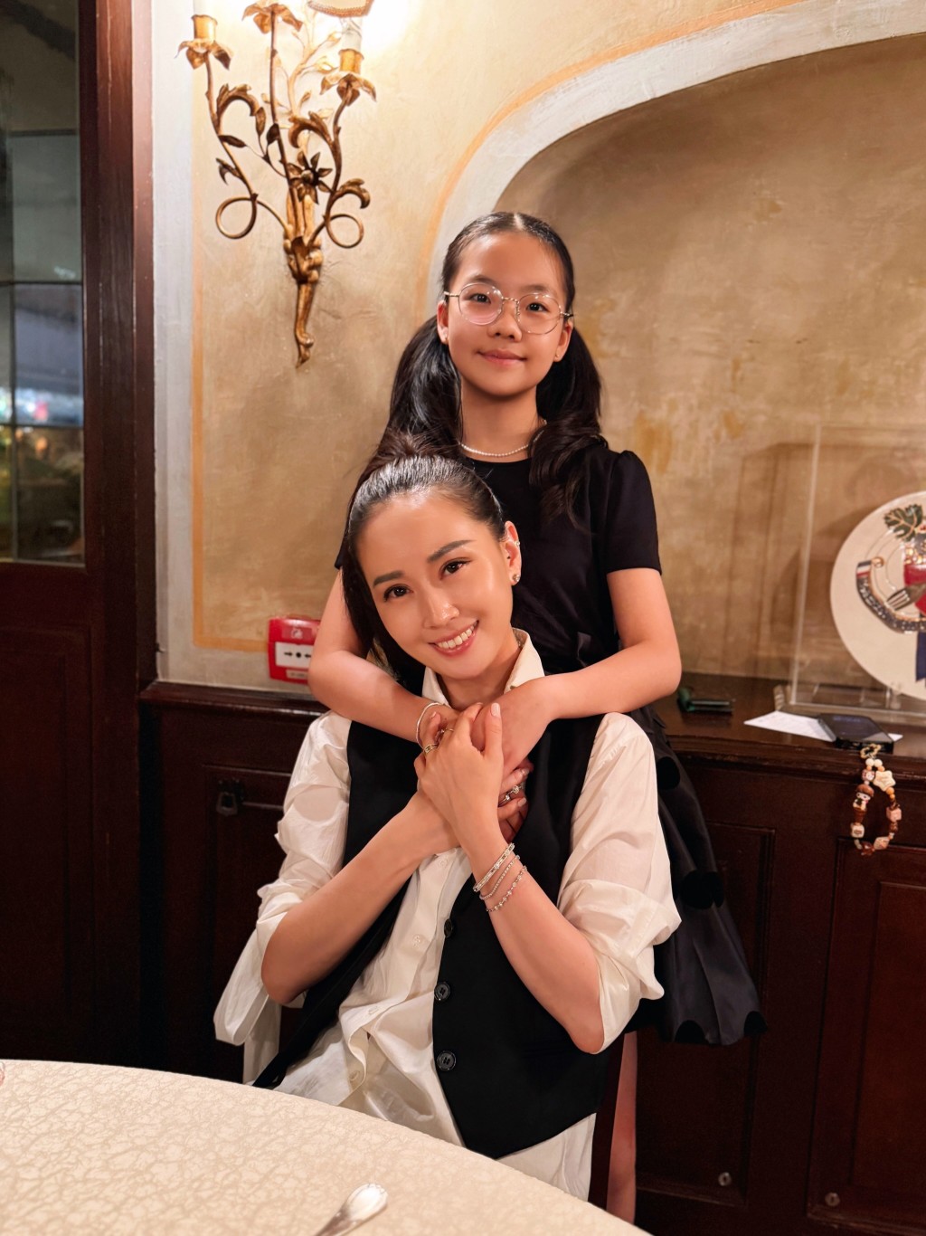 女兒從後擁抱媽咪，兩母女樣貌相似，顏值很高。