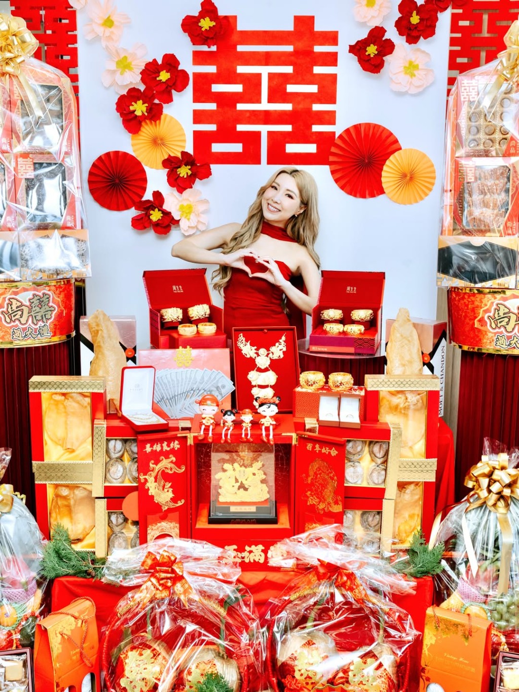 待嫁新娘譚嘉儀在眾多禮品前,幸福地做出心形手勢。