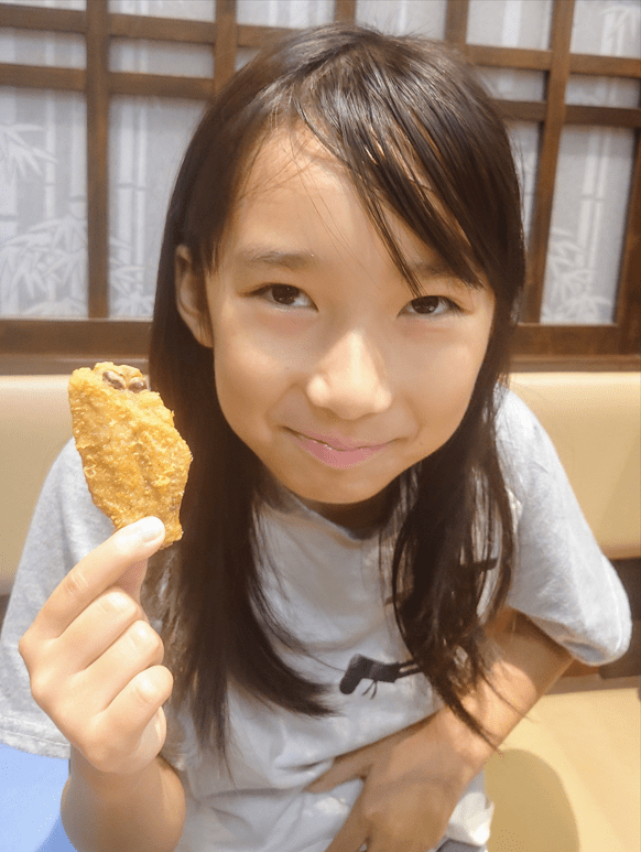 平田琉七手拿炸雞翼,展露招牌純真笑容。