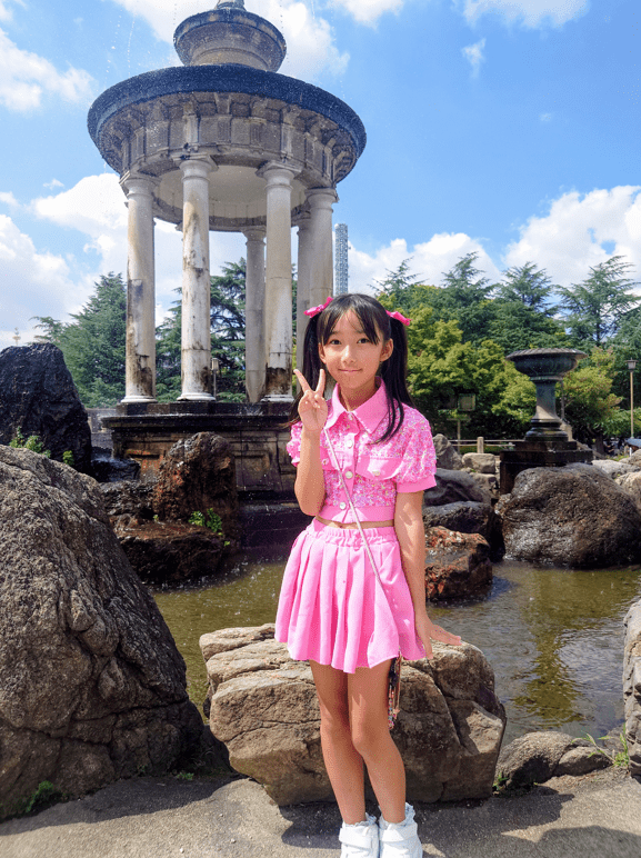 平田琉七在公園噴水池前,比出招牌「V」手勢留影。