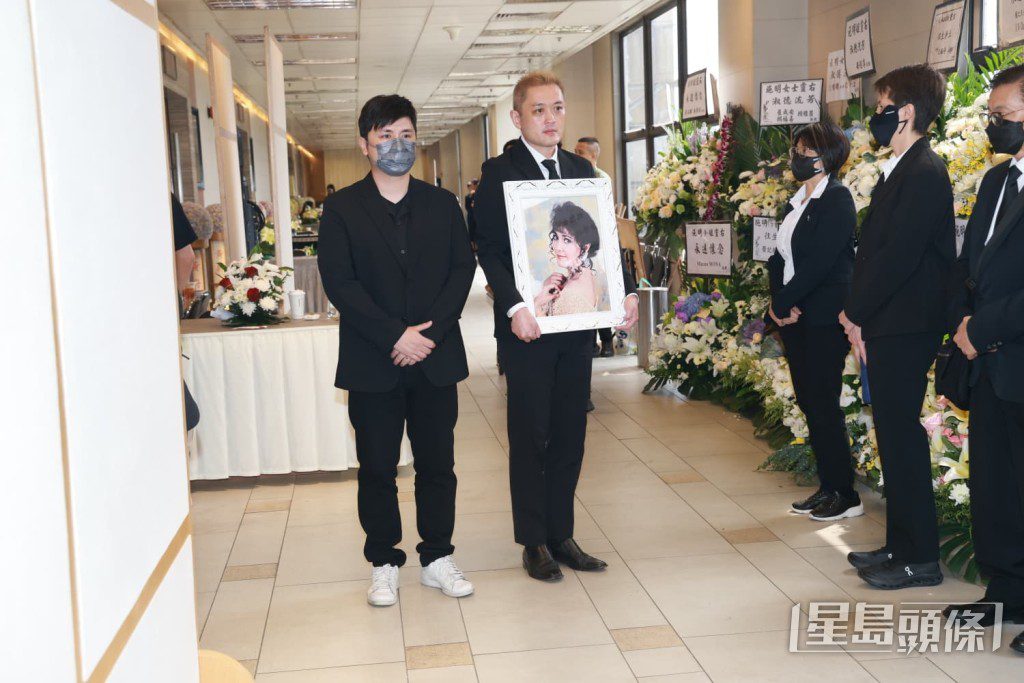 李泳漢捧着母親施明的遺照步出靈堂。