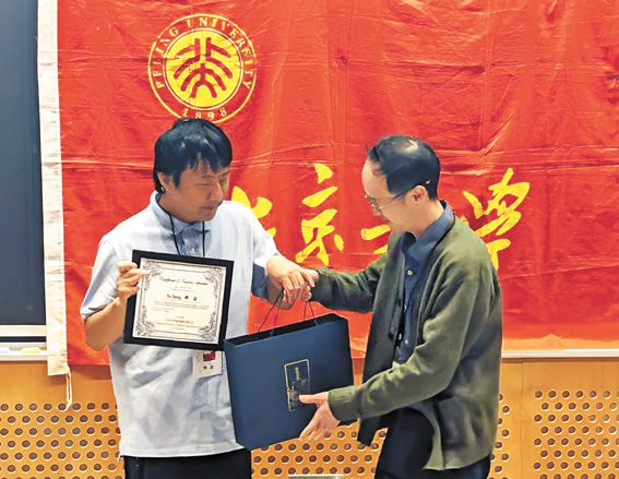 鄧煜(左)演講之後接受北大新英格蘭校友會贈送的禮物。 李強攝