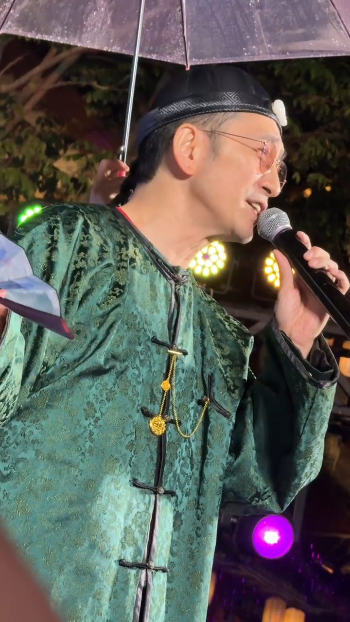 吳啟華近日身穿「方唐鏡」的綠色清裝,在雨中獻唱。