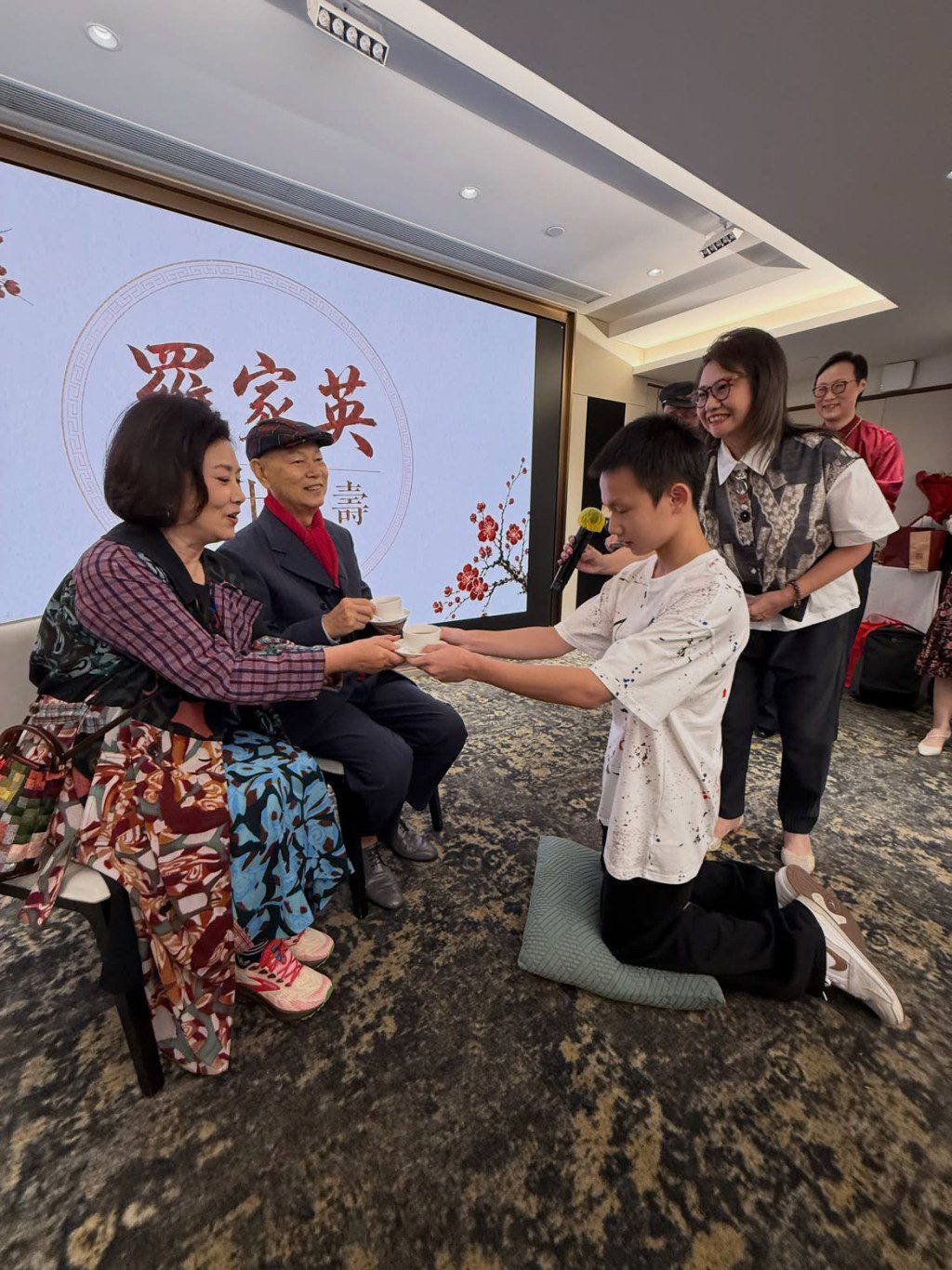 羅家英與汪明荃在壽宴上接受晚輩跪地敬茶。