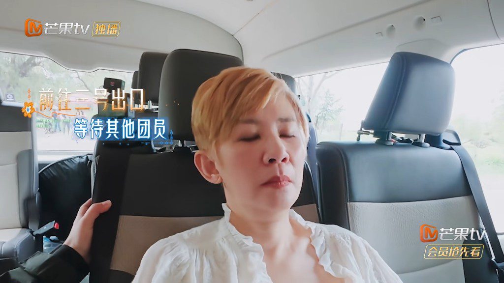 旅遊巴駛往出口等候時,身體不適的吳君如閉目仰躺在座椅上休息。