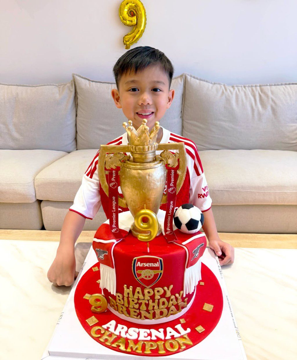 桌上放著一個精緻的英超冠軍獎盃造型蛋糕，寫有「ARSENAL CHAMPION」。