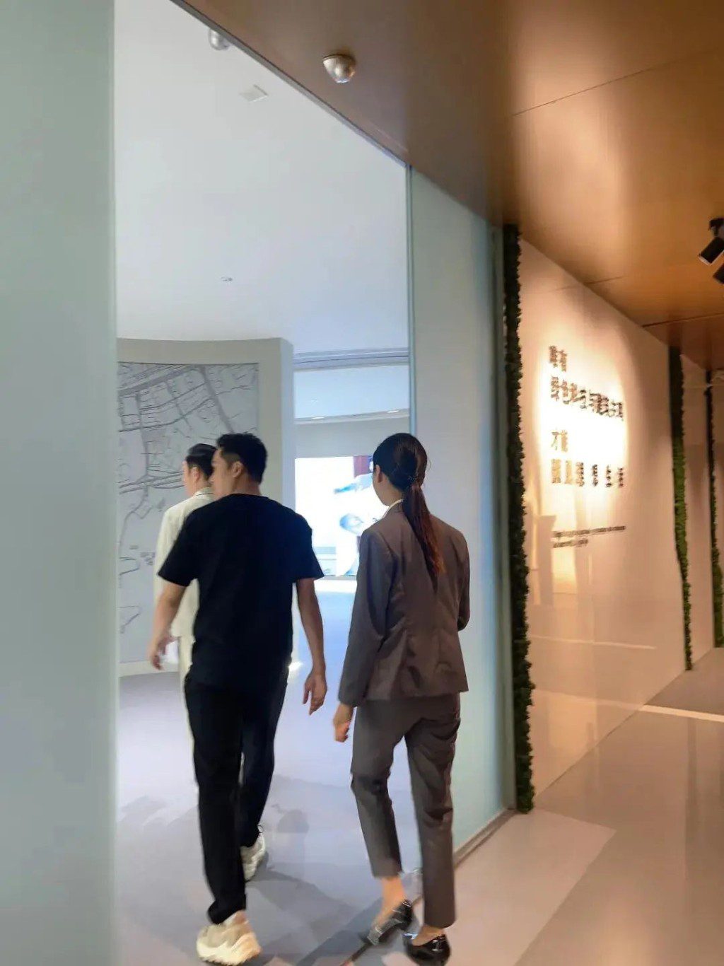 照片中,吳啟華身穿西裝,在銷售人員陪同下參觀單位。