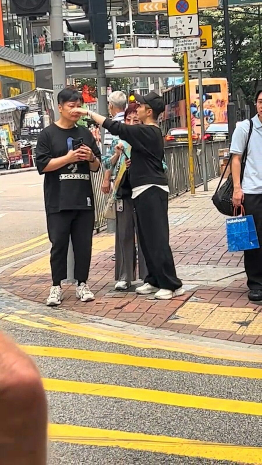 湯盈盈在街頭伸出手,細心地為老公錢嘉樂整理頭髮與面部。