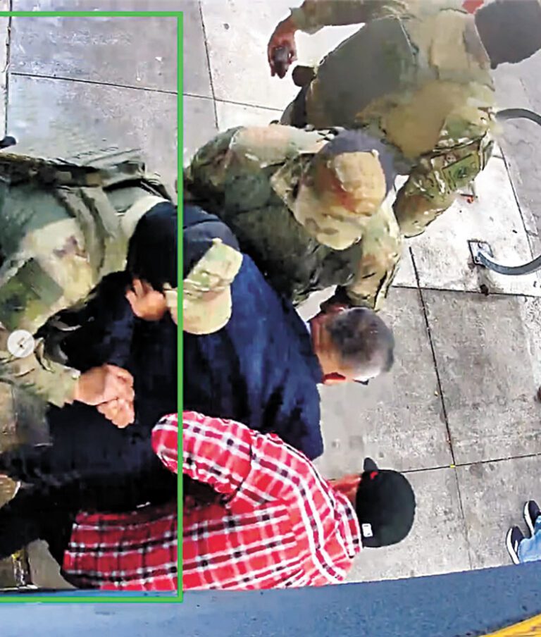 三名ICE制服人員與一名紅色格仔衫便衣人員合力控制藍色西裝男子，將其雙手扳至背後。監控視頻截圖