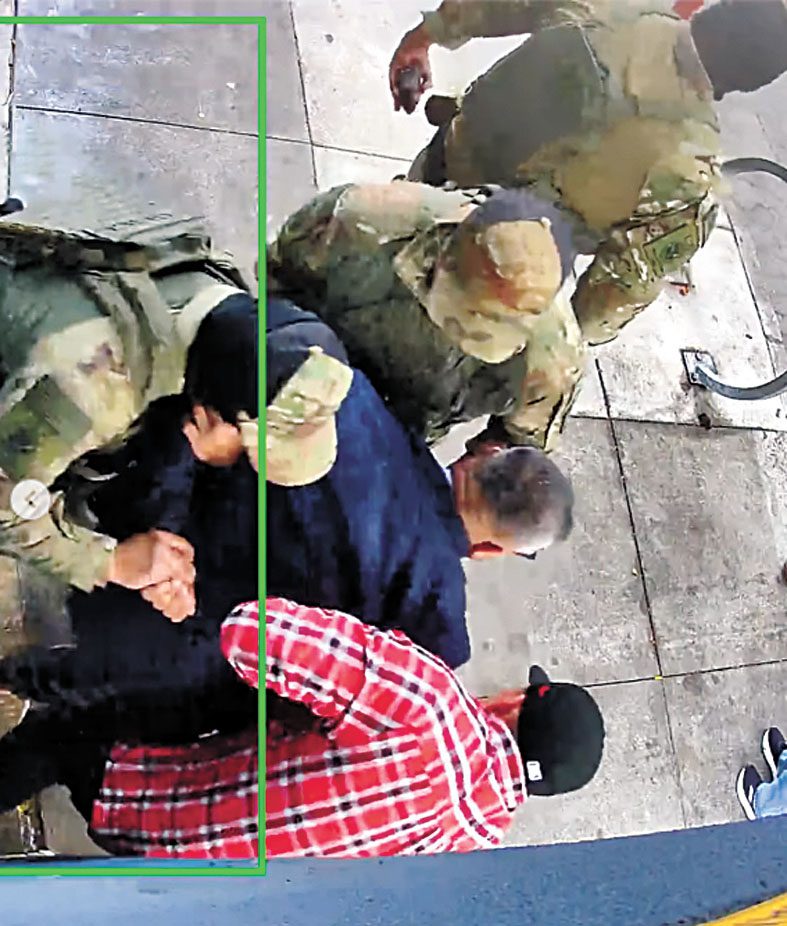 三名ICE制服人員與一名紅色格仔衫便衣人員合力控制藍色西裝男子,將其雙手扳至背後。監控視頻截圖