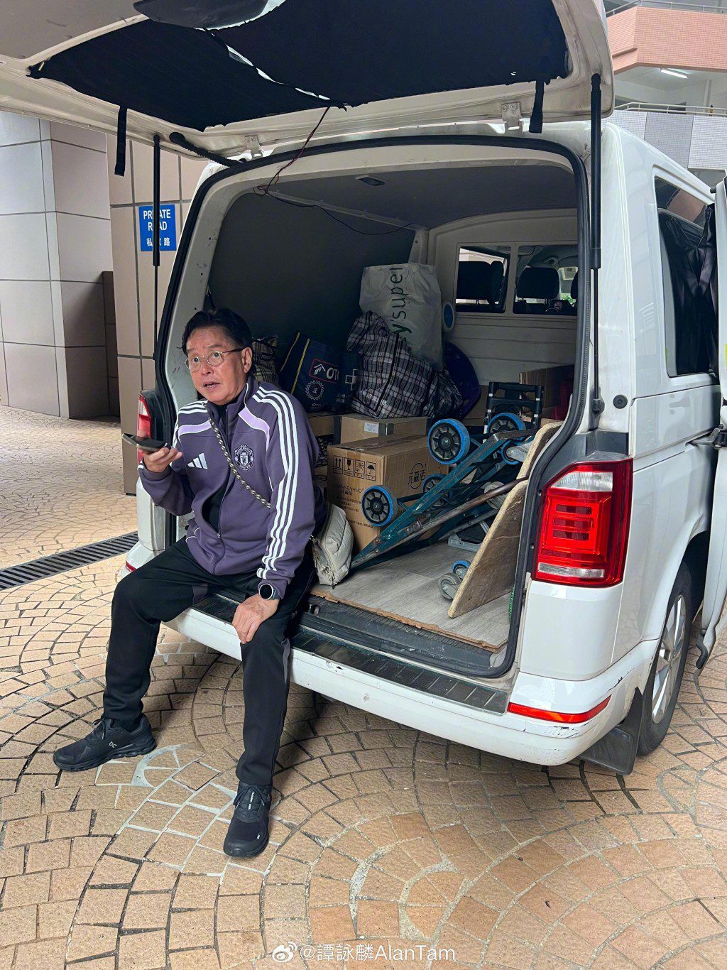譚詠麟坐在貨車車尾,逐一通知朋友他將親自送上紅酒。