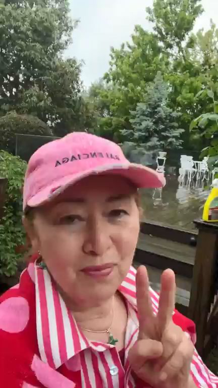 張瑪莉在寬敞木露台比出V字手勢,身後是雨中白色鐵藝桌椅。