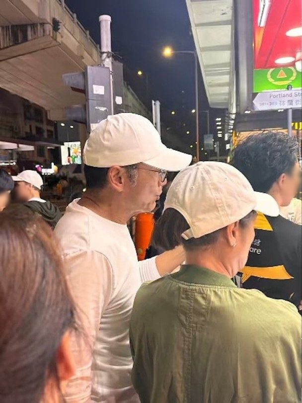 周潤發排隊等候時,與旁人談笑風生。